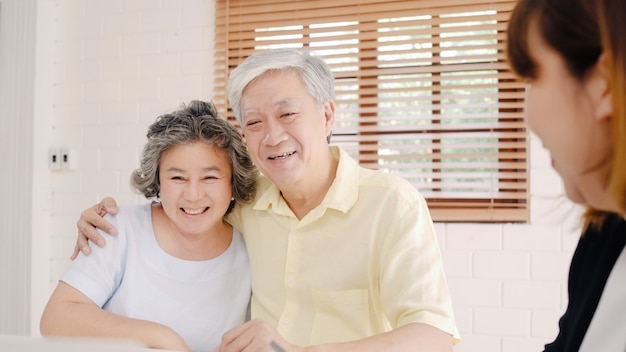 Asia agente femenina inteligente ofrece seguro de salud para parejas mayores por documento, tableta y computadora portátil.