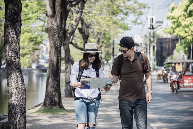 Asiancouple turista sosteniendo el mapa de la ciudad cruzando la carretera