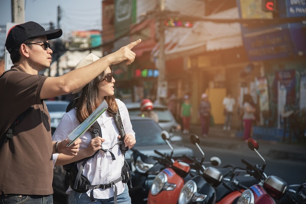 Asiancouple turista sosteniendo el mapa de la ciudad cruzando la carretera