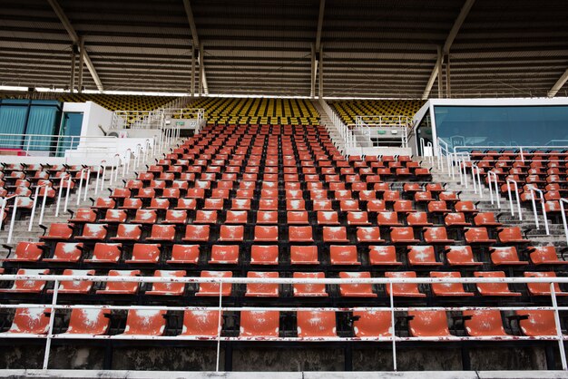 Asientos plásticos vacíos y viejos rojos en el estadio.