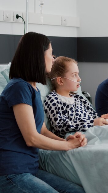 Asisstant pediátrico afroamericano monitoreando a un niño enfermo discutiendo el tratamiento de recuperación