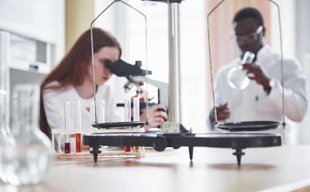 Asistente de laboratorio con bulbo de cristalería de laboratorio microscopio con productos químicos.