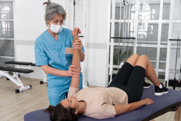 Asistente médico ayudando al paciente con ejercicios de fisioterapia