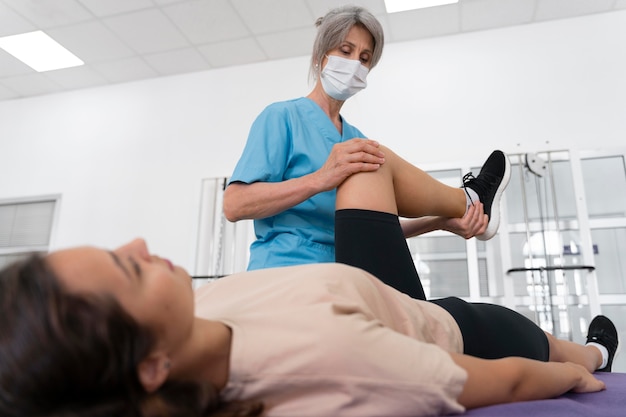 Foto gratuita asistente médico ayudando al paciente con ejercicios de fisioterapia