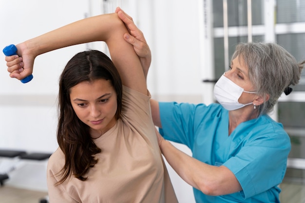 Asistente médico ayudando al paciente con ejercicios de fisioterapia