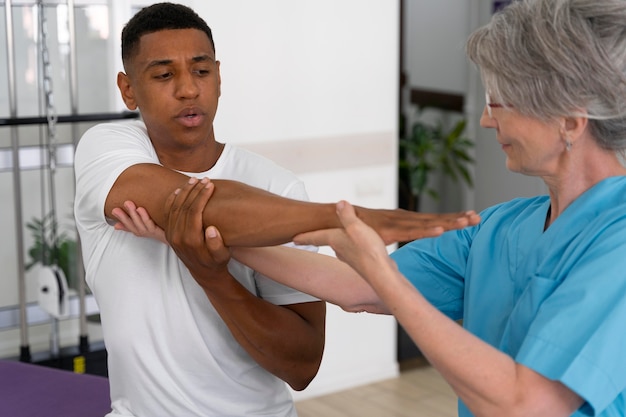 Asistente médico ayudando al paciente con ejercicios de fisioterapia