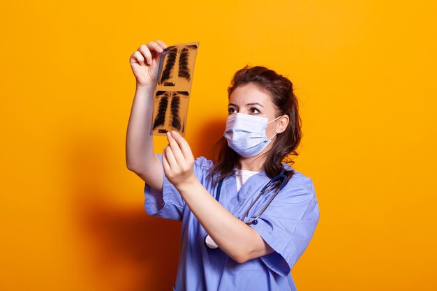 Foto gratuita asistente médico con mascarilla analizando radiografía