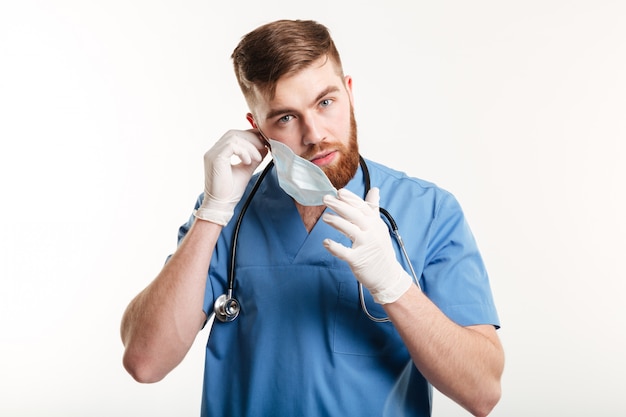 Asistente médico masculino con estetoscopio quitándose la máscara