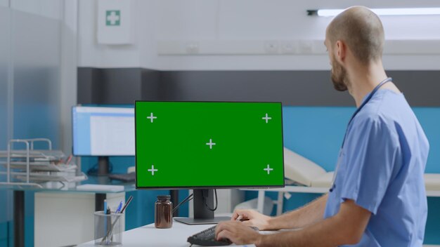 Asistente médico sentado en el escritorio trabajando con experiencia en enfermedades escribiendo un informe médico en una computadora con llave croma de pantalla verde simulada con una pantalla aislada en la oficina del hospital. concepto de medicina