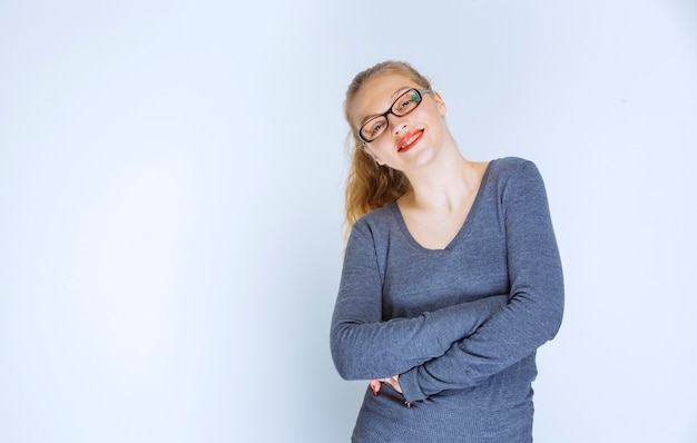 Asistente rubia con anteojos sonriendo y dando poses profesionales.