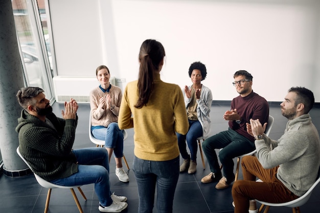 Asistentes de terapia de grupo aplaudiendo a uno de los participantes durante la reunión