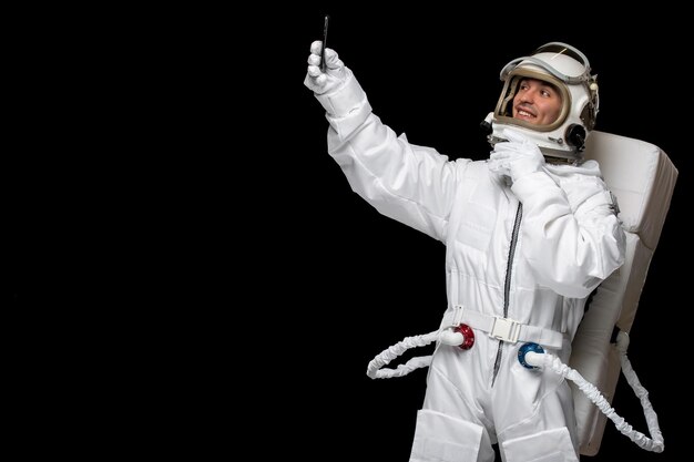 Astronauta día astronauta en galaxia traje espacial casco sosteniendo teléfono tomando selfie sonriendo feliz