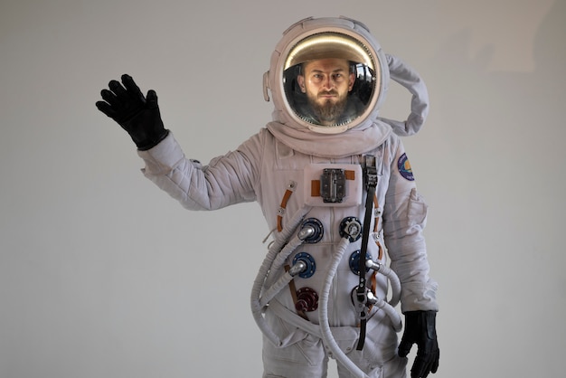 Astronauta masculino completamente equipado saludando en su traje espacial