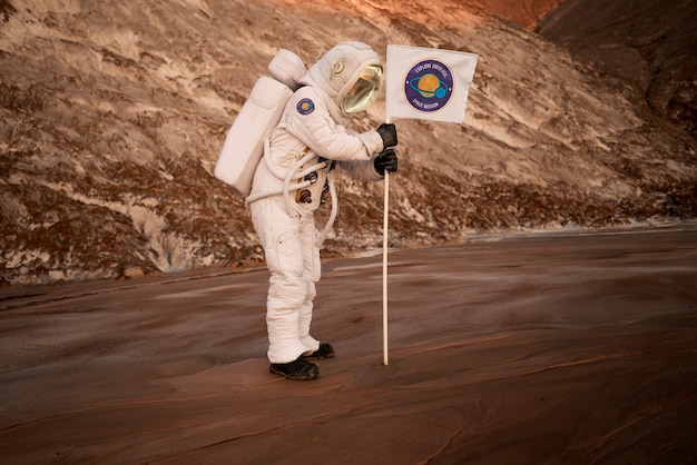 Foto gratuita astronauta masculino pegando una bandera en el suelo en un planeta desconocido