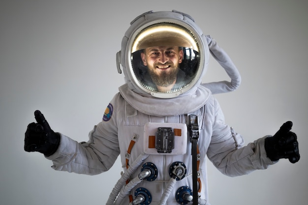Astronauta masculino totalmente equipado sonriendo y mostrando los pulgares hacia arriba