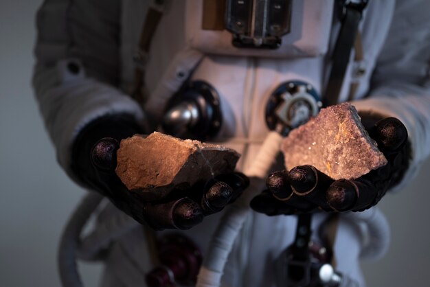 Astronauta masculino totalmente equipado sosteniendo dos rocas