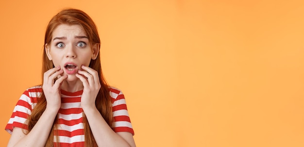 Foto gratuita asustado conmocionado pelirroja mujer preocupación mirar cámara sin palabras jadeando preocupado toque labios caída mandíbula ast