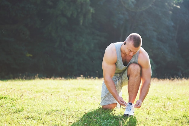 Atar calzado deportivo. un joven deportista preparándose para el entrenamiento atlético y físico al aire libre.