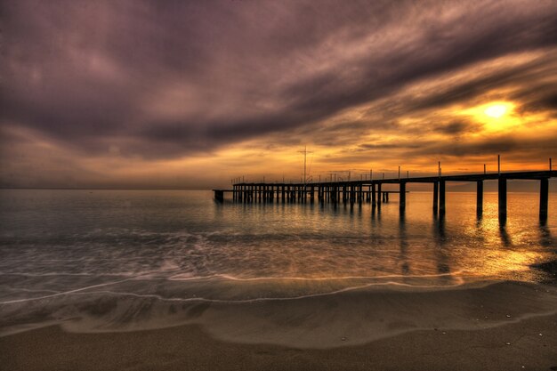 Atardecer en la playa junto al muelle