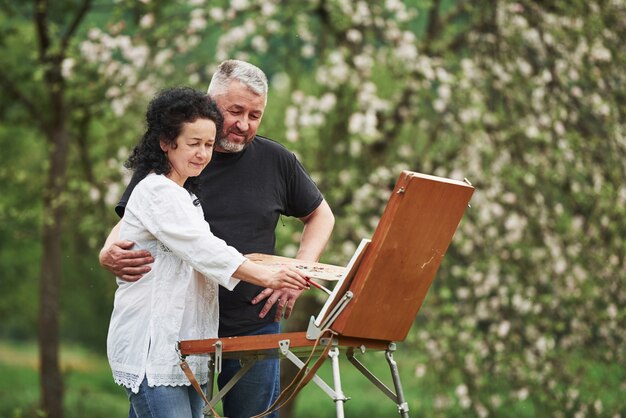 Atención a los detalles. Pareja madura tiene días de ocio y trabajando juntos en la pintura en el parque