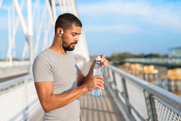 Atleta atractivo abriendo una botella de agua antes del entrenamiento