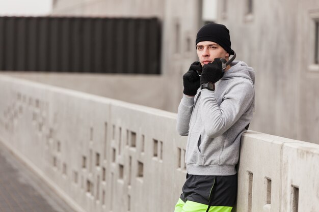 Atleta con auriculares sujetándose contra un muro