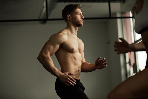 Atleta de construcción muscular calentándose mientras tiene clase de ejercicio en un gimnasio