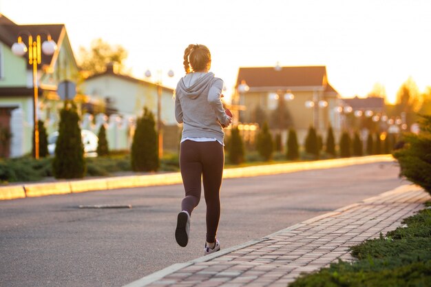 Atleta corredor corriendo en carretera. Mujer fitness trotar entrenamiento concepto de bienestar.