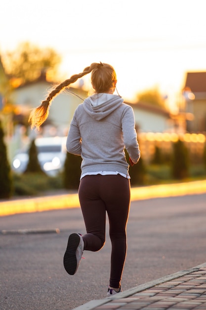 Atleta corredor corriendo en carretera. Mujer fitness trotar entrenamiento concepto de bienestar.