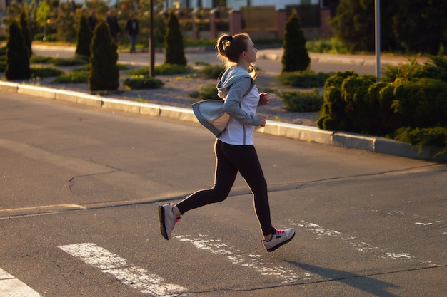 Atleta corredor corriendo en carretera. Mujer fitness trotar entrenamiento concepto de bienestar.