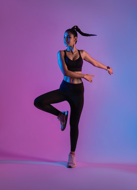 Atleta deportista asiática saltando baile como parte del entrenamiento para quemar grasa en el estudio de fitness