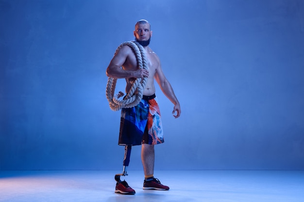 Atleta con discapacidad o amputado aislado en la pared azul del estudio