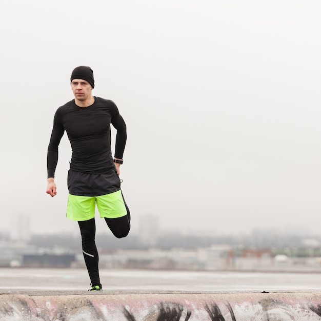 Foto gratuita atleta estirando en un día gris