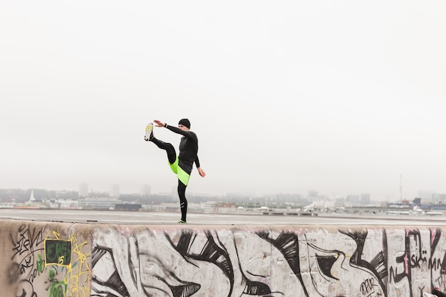 Atleta estirando en muro