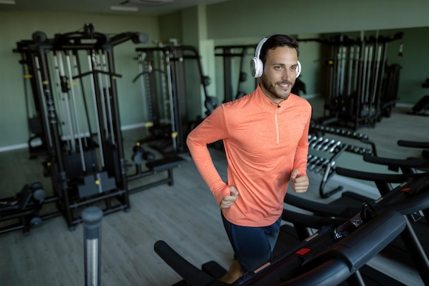 Foto gratuita atleta feliz corriendo en cinta rodante durante el entrenamiento deportivo en el club de salud