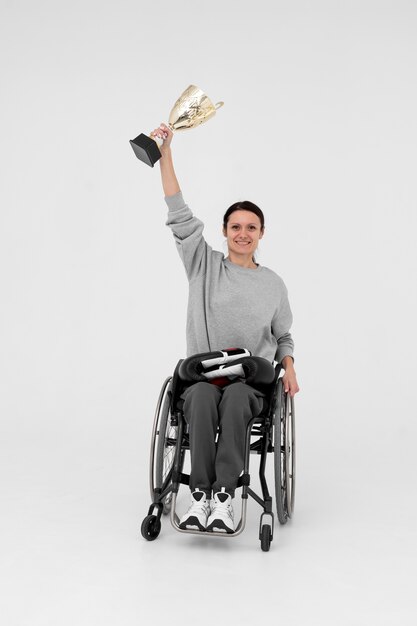 Atleta femenina discapacitada sosteniendo una copa de oro
