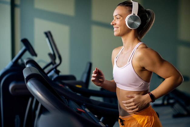 Atleta femenina feliz corriendo en cinta rodante en un gimnasio