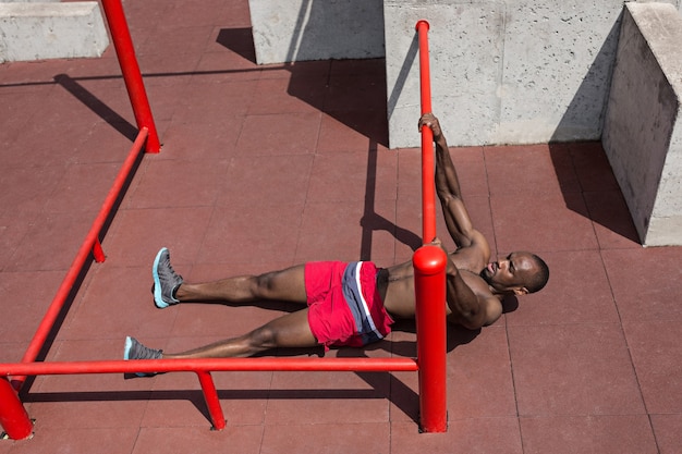 Foto gratuita el atleta en forma haciendo ejercicios en el estadio. hombre afroamericano o afroamericano al aire libre en la ciudad. tire hacia arriba de los ejercicios deportivos. fitness, salud, concepto de estilo de vida