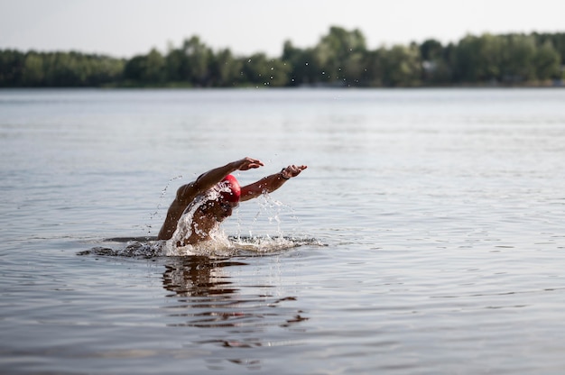 Foto gratuita atleta con gorra roja nadando en el lago