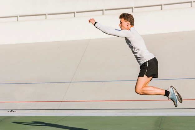Atleta haciendo un salto de longitud con copia espacio.