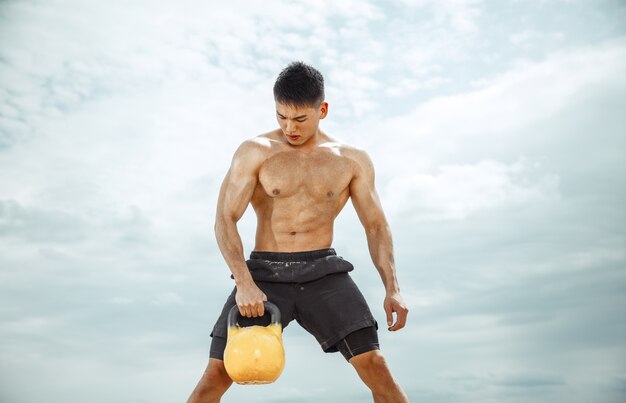 Atleta joven sano haciendo ejercicio con el peso en la playa