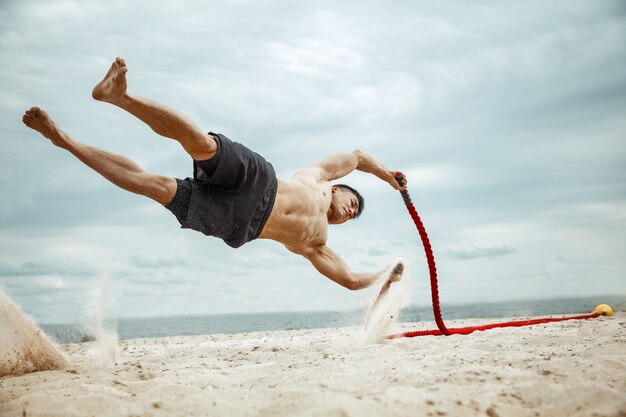 Atleta joven sano haciendo sentadillas en la playa