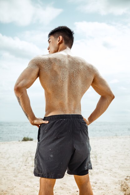 Atleta joven sano haciendo sentadillas en la playa