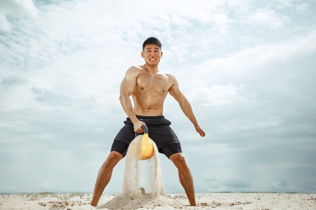 Atleta joven sano haciendo sentadillas en la playa