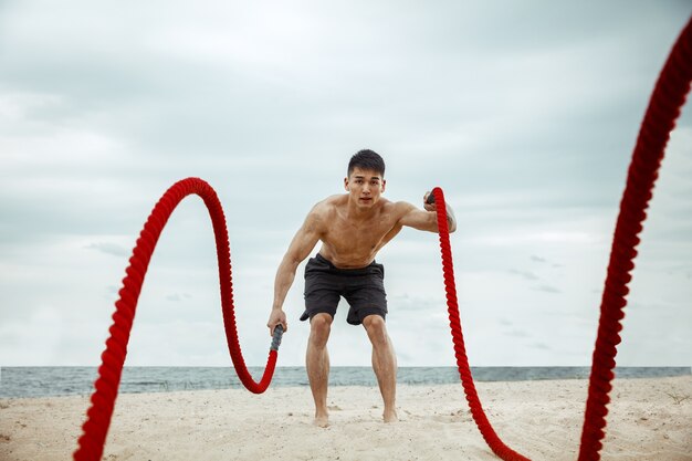 Atleta joven sano haciendo sentadillas en la playa