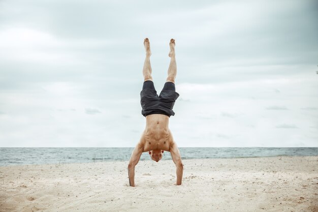 Atleta joven sano haciendo sentadillas en la playa