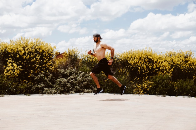 Atleta masculino sin camisa corriendo cerca de campo