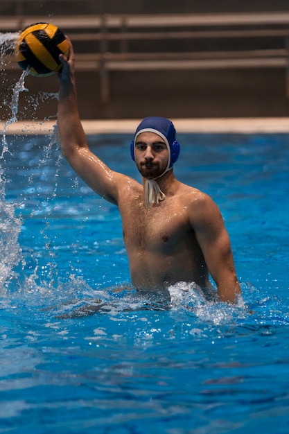 Atleta masculino jugando al waterpolo en la piscina cubierta