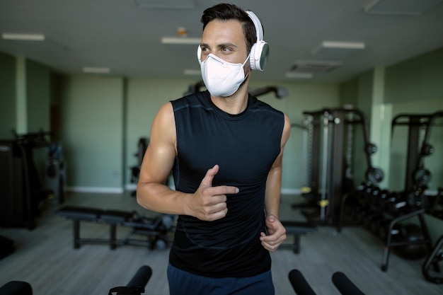 Foto gratuita atleta masculino con mascarilla protectora mientras corre en cinta rodante