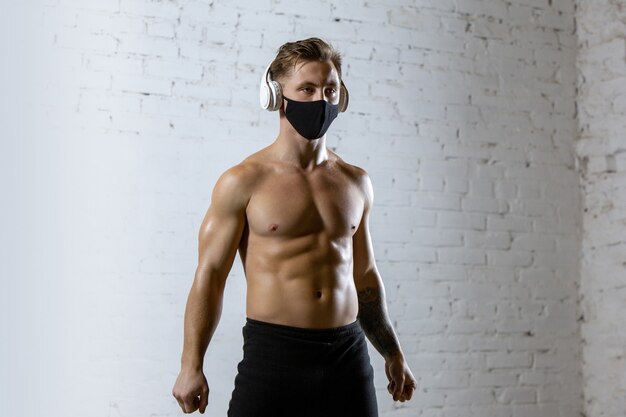 Atleta masculino profesional entrenando en la pared de ladrillo con mascarilla.